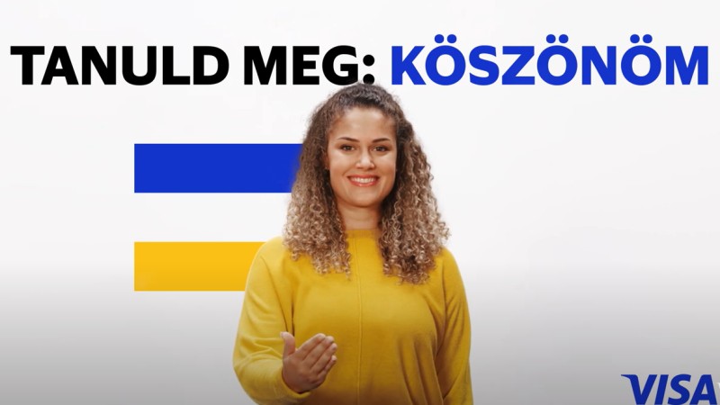 woman in yellow in front of visa flag and tanuld meg koszonom