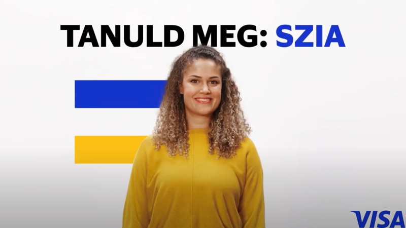 woman in yellow in front of visa flag and tanuld meg szia
