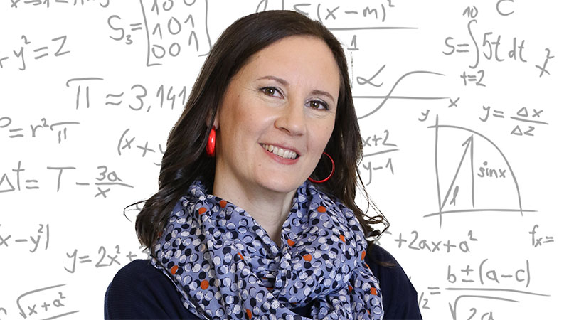 woman smiling in front of math equations on board